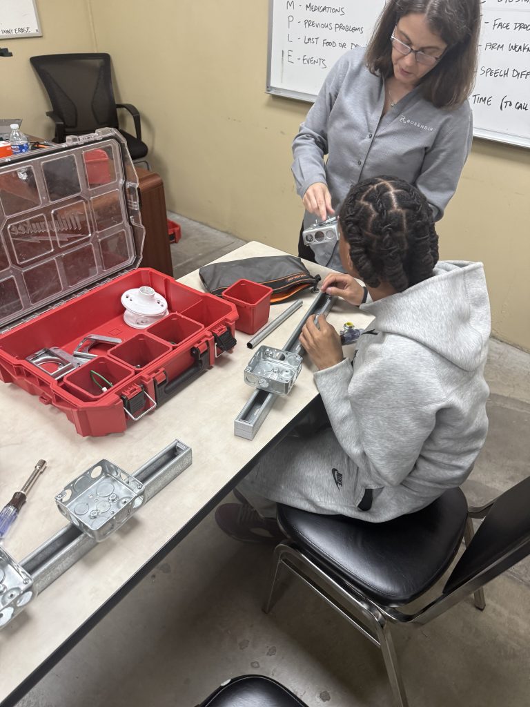 A student and an electrical engineer working together on an outlet installation activity. 